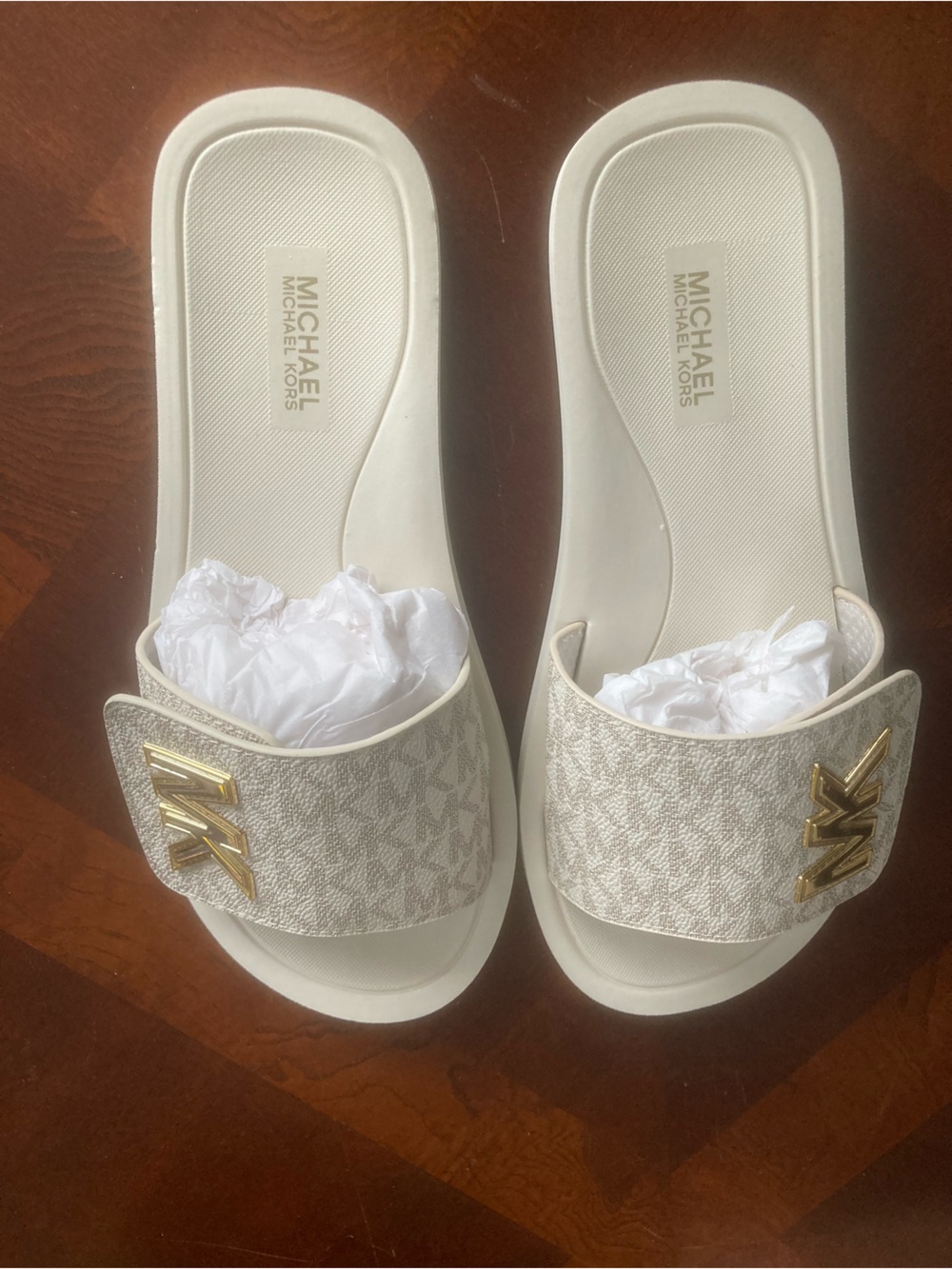 Michael Kors slide sandals in white with signature MK logo hardware. Easy slip-o